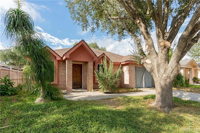 ranch-style house with driveway, a front yard, fence, and brick siding