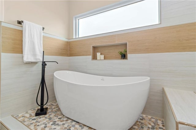 bathroom with tile patterned floors, a bathing tub, and tile walls