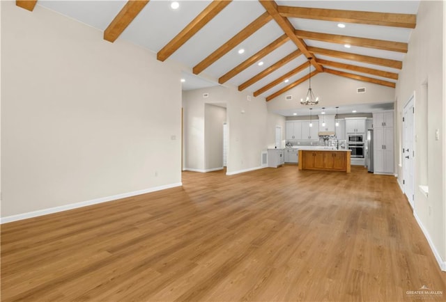 unfurnished living room featuring a notable chandelier, beam ceiling, high vaulted ceiling, and light hardwood / wood-style flooring