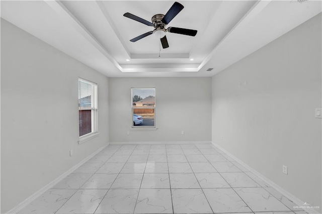 spare room featuring a raised ceiling and ceiling fan