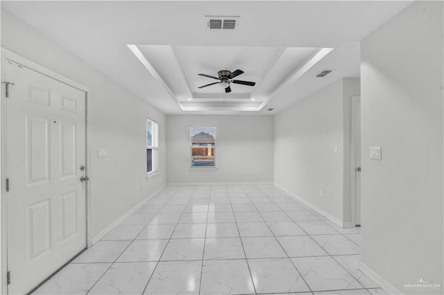 interior space with ceiling fan and a raised ceiling