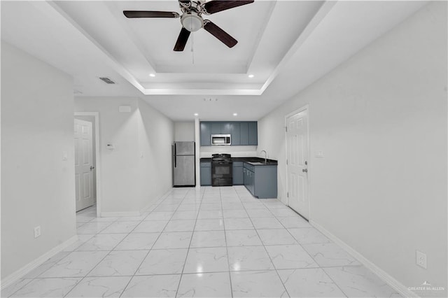 kitchen with sink, a tray ceiling, stainless steel appliances, and ceiling fan