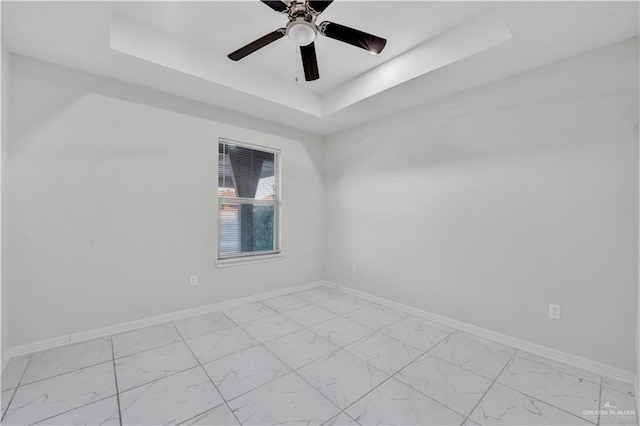 unfurnished room with ceiling fan and a tray ceiling