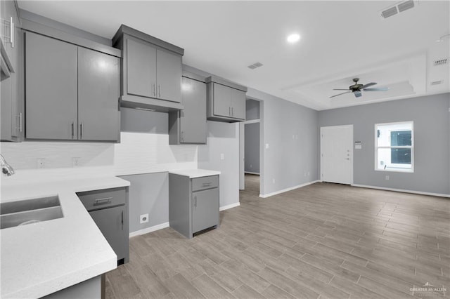 kitchen featuring a sink, visible vents, open floor plan, light countertops, and gray cabinets