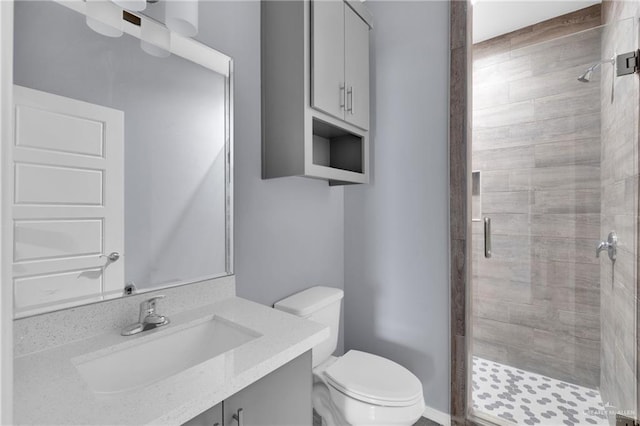 bathroom with toilet, a stall shower, and vanity