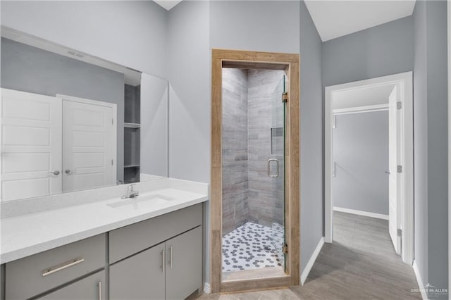 bathroom featuring a stall shower, vanity, baseboards, and wood finished floors