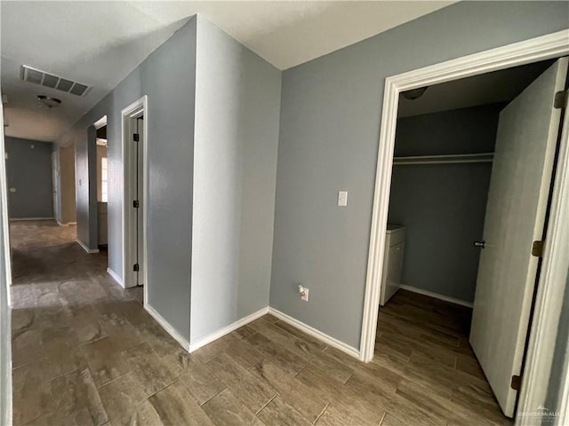 corridor with baseboards, visible vents, and wood tiled floor