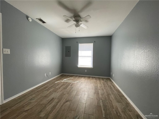 empty room featuring visible vents, baseboards, dark wood finished floors, electric panel, and a ceiling fan