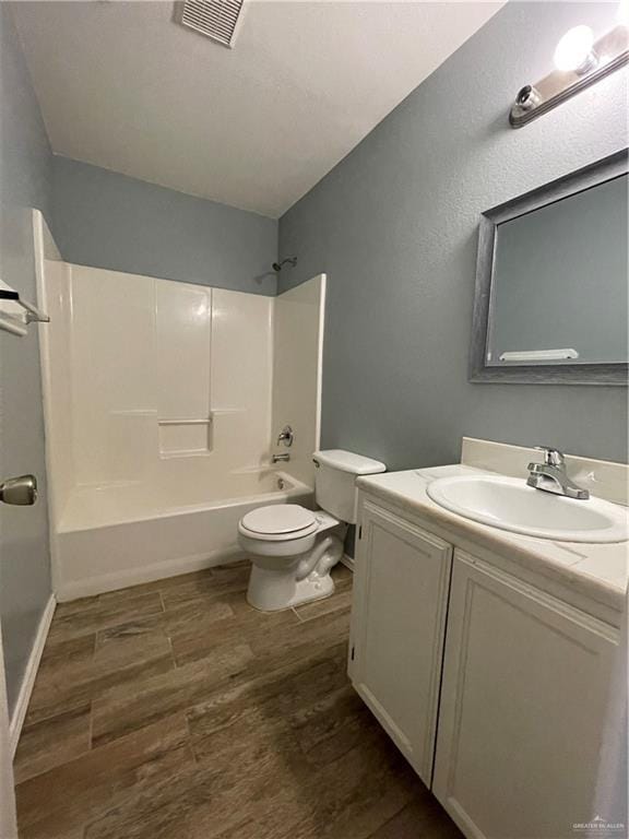 bathroom with visible vents, toilet, wood finished floors, washtub / shower combination, and vanity