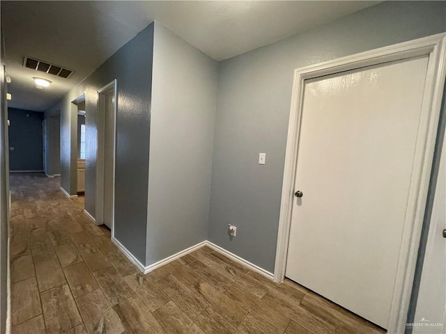 hallway featuring visible vents, baseboards, and wood finished floors