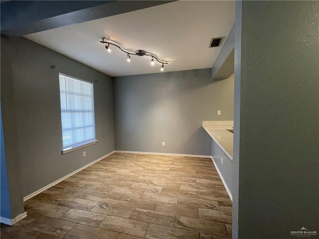 empty room featuring visible vents, wood finish floors, and baseboards