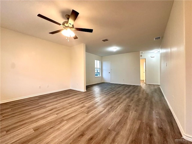 spare room with a ceiling fan, visible vents, baseboards, and wood finished floors