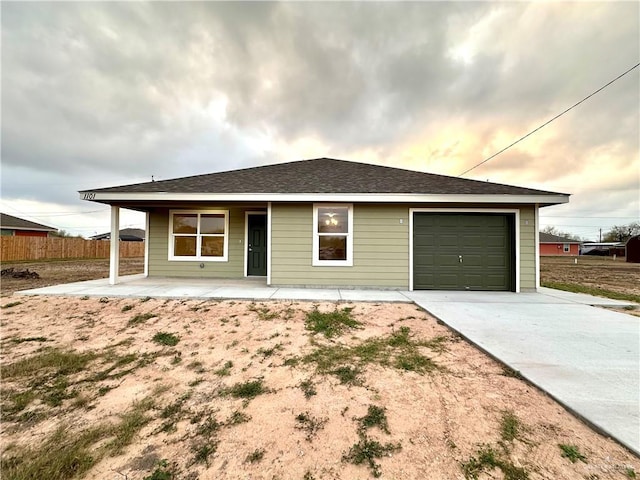 ranch-style house with a garage, concrete driveway, a shingled roof, and fence