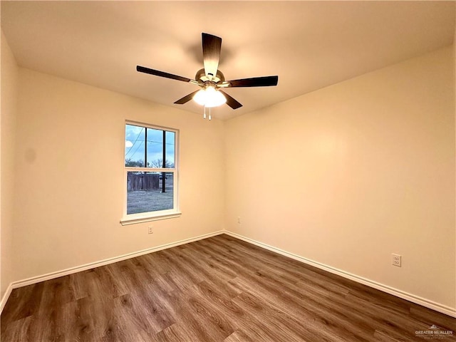 empty room with a ceiling fan, baseboards, and dark wood-style flooring