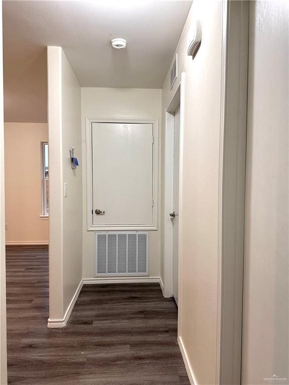 corridor with baseboards, visible vents, and dark wood finished floors