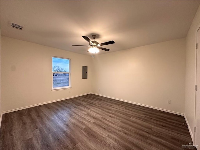 spare room featuring visible vents, dark wood-type flooring, a ceiling fan, electric panel, and baseboards