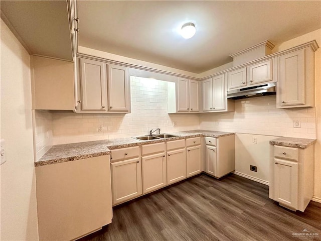 kitchen with dark wood-style floors, light countertops, decorative backsplash, a sink, and under cabinet range hood