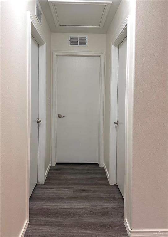 corridor with dark wood-style floors, baseboards, and visible vents