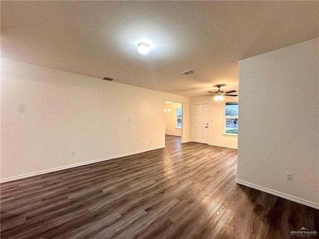 spare room featuring a ceiling fan, visible vents, dark wood finished floors, and baseboards