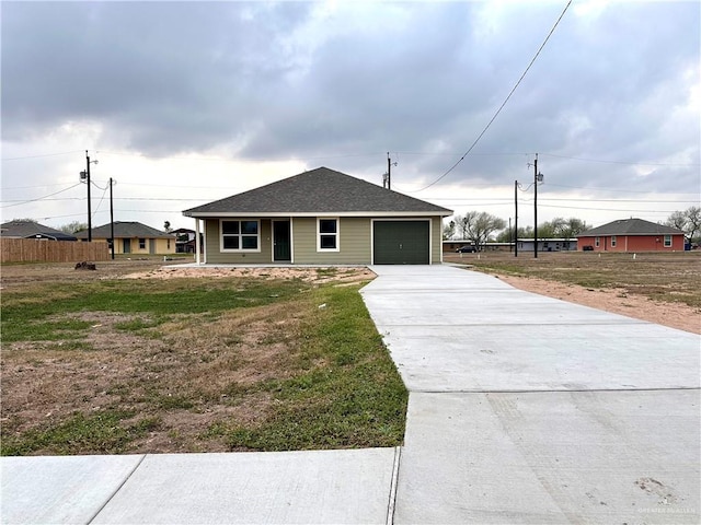 view of front of property featuring a garage, fence, concrete driveway, and roof with shingles