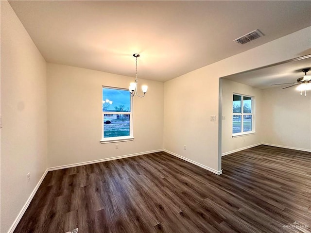 unfurnished dining area with baseboards, visible vents, dark wood finished floors, and ceiling fan with notable chandelier