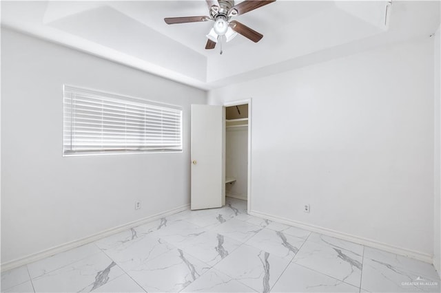 unfurnished bedroom featuring a raised ceiling and ceiling fan