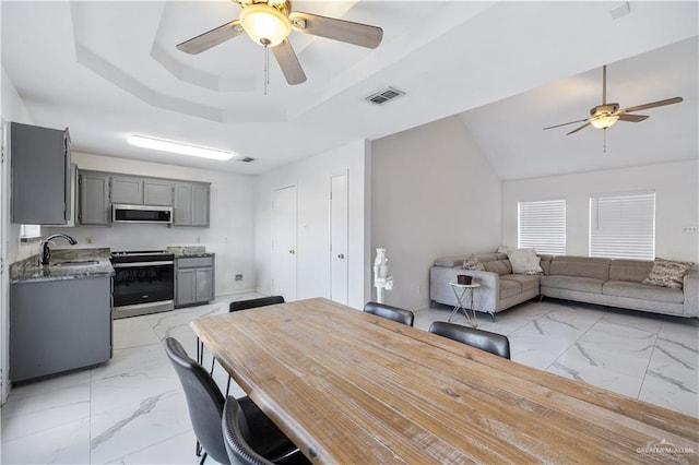 dining space featuring sink, a raised ceiling, and ceiling fan