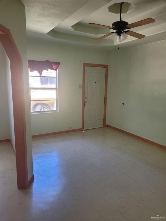 233 W 4th St, La Joya, TX 78560 - empty room featuring a ceiling fan, baseboards, arched walkways, and a raised ceiling