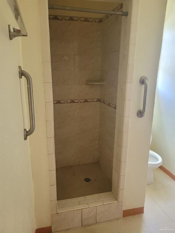 233 W 4th St, La Joya, TX 78560 - bathroom with a shower stall, tile patterned flooring, toilet, and baseboards
