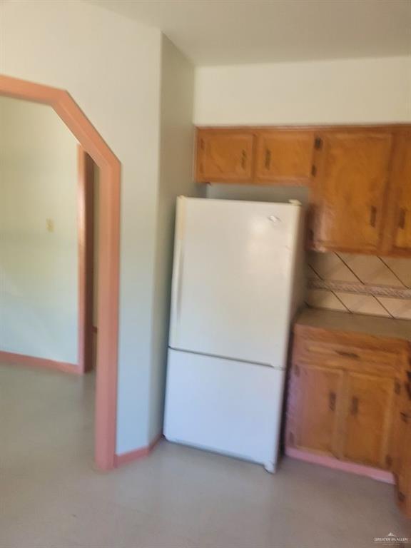233 W 4th St, La Joya, TX 78560 - kitchen featuring freestanding refrigerator and brown cabinetry