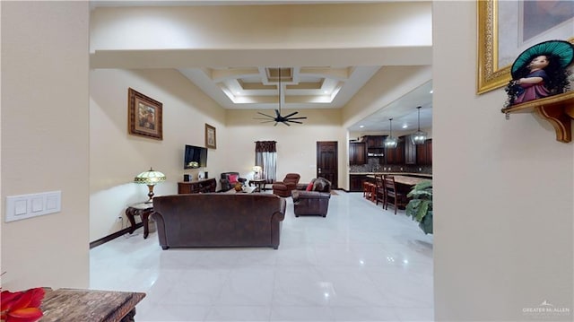 living room featuring a tray ceiling, ceiling fan, and coffered ceiling