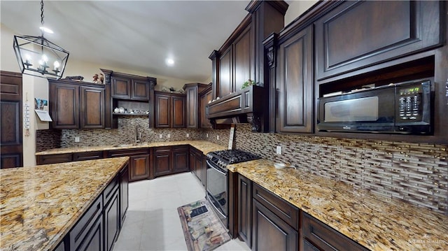 kitchen featuring stainless steel gas stove, sink, light stone counters, backsplash, and decorative light fixtures