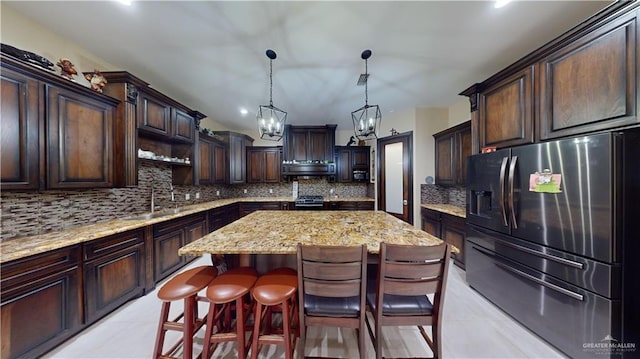 kitchen featuring a center island, hanging light fixtures, decorative backsplash, dark brown cabinets, and stainless steel appliances