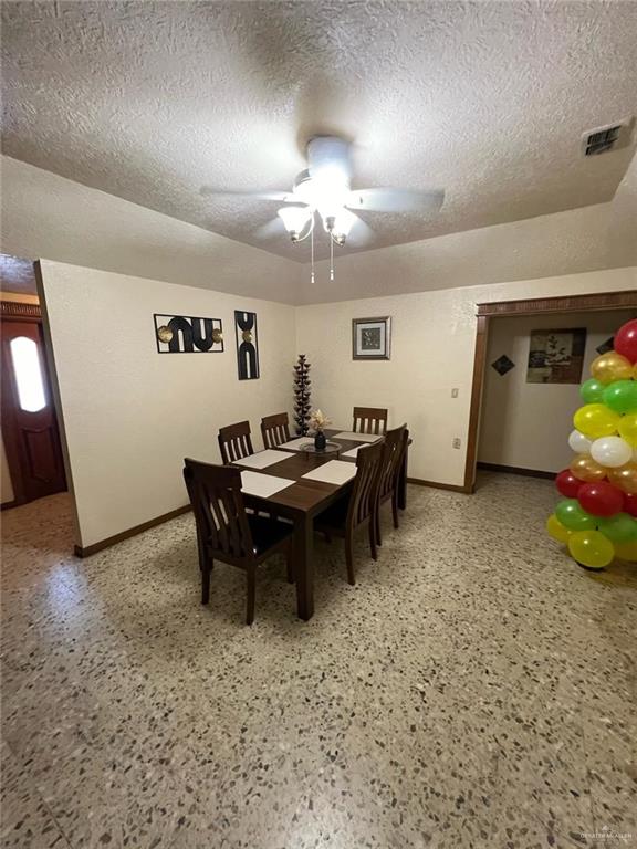 dining room with light speckled floor, ceiling fan, a textured ceiling, and baseboards