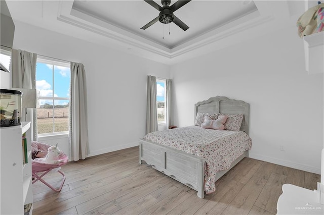 bedroom featuring ceiling fan, light hardwood / wood-style floors, and a raised ceiling