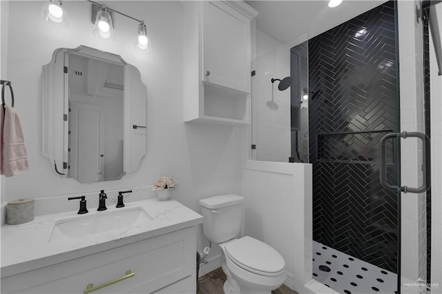 bathroom with vanity, toilet, and a shower with door