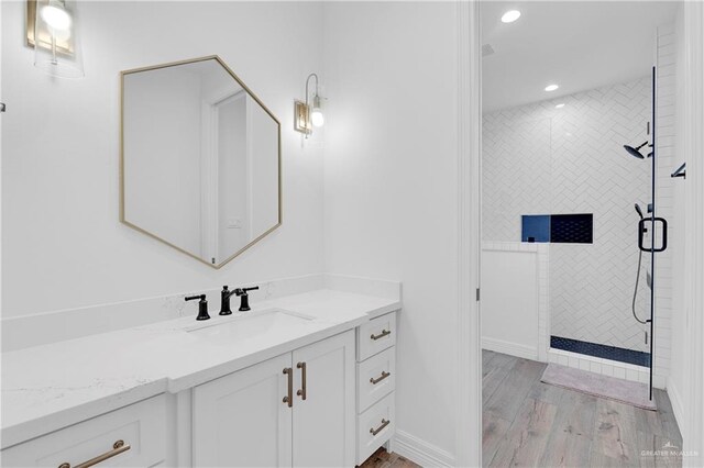 bathroom with a tile shower, vanity, and hardwood / wood-style flooring