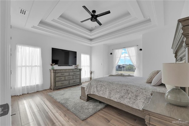 bedroom featuring a tray ceiling, ceiling fan, and light hardwood / wood-style flooring