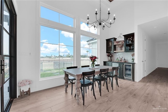 dining area with bar, a high ceiling, light hardwood / wood-style flooring, and beverage cooler