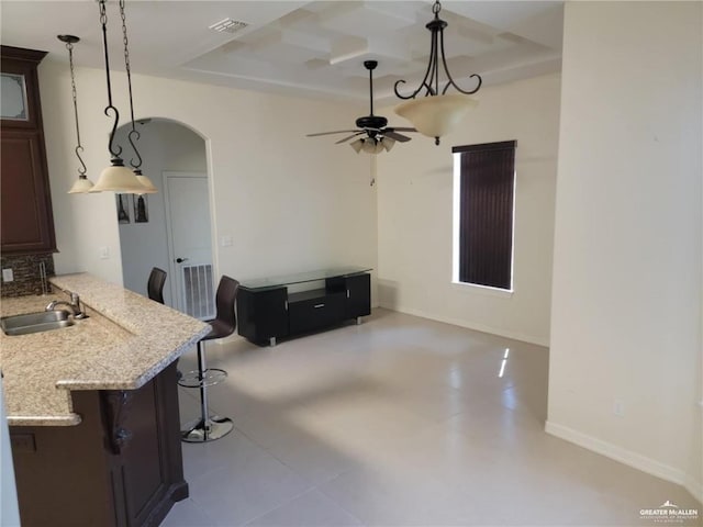 kitchen featuring pendant lighting, sink, a tray ceiling, and a breakfast bar area