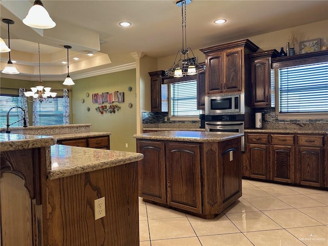 5845 Acacia St, Harlingen, TX 78552 - kitchen featuring stainless steel appliances, a chandelier, light tile patterned flooring, backsplash, and crown molding