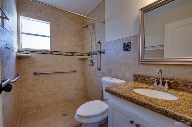 bathroom with vanity, tile walls, toilet, and tiled shower