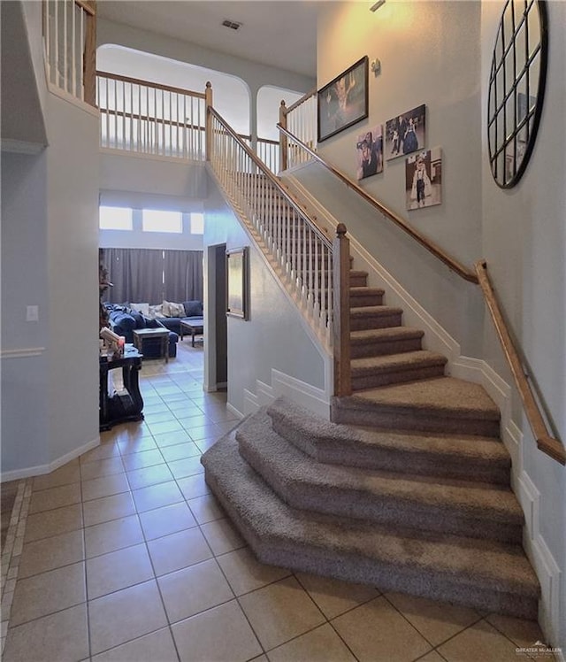 staircase featuring tile patterned floors and a towering ceiling