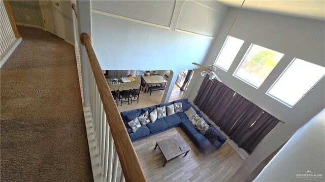 living room with wood-type flooring, a towering ceiling, and ceiling fan