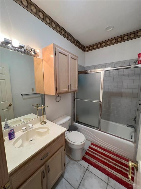 full bathroom with combined bath / shower with glass door, vanity, tile patterned floors, and toilet