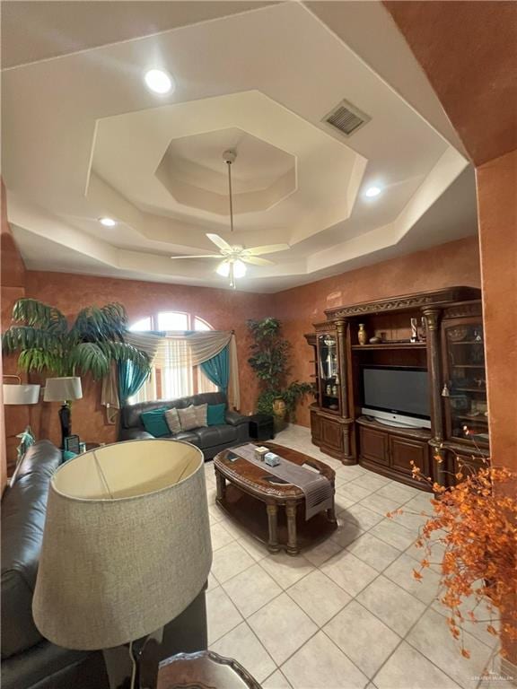 living room with ceiling fan, light tile patterned flooring, and a tray ceiling