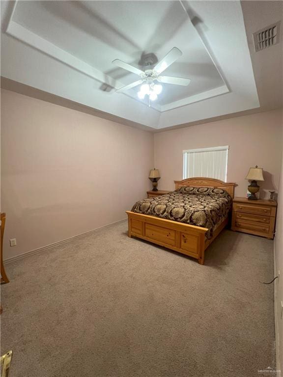 carpeted bedroom with ceiling fan and a tray ceiling