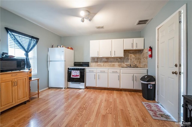 kitchen featuring range with gas stovetop, a sink, black microwave, visible vents, and freestanding refrigerator