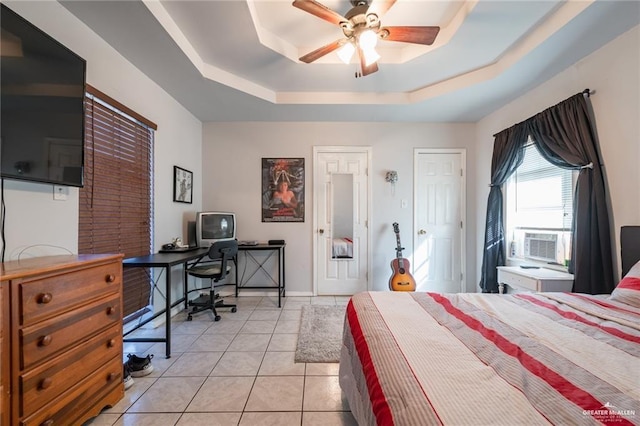 bedroom with light tile patterned floors, a tray ceiling, cooling unit, a ceiling fan, and baseboards