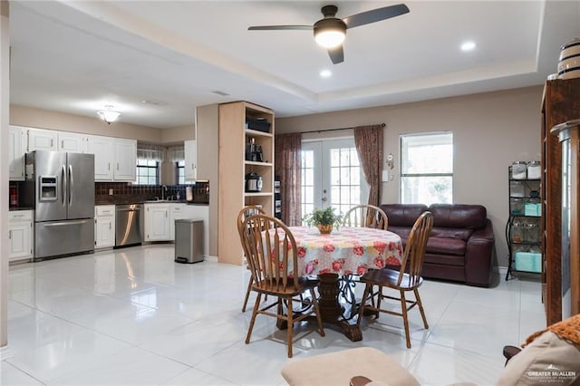 dining space with recessed lighting, ceiling fan, french doors, and a tray ceiling